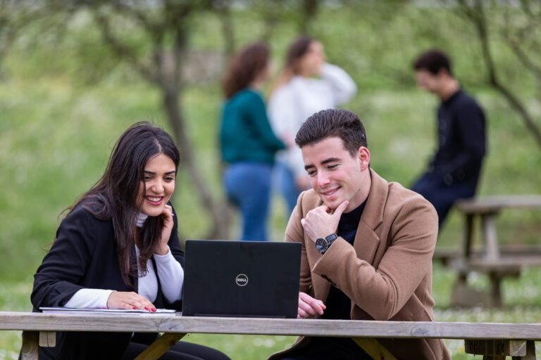 Photo de deux alternants devant un bâtiment de la MAIF présentant un environnement d'accueil et de service.