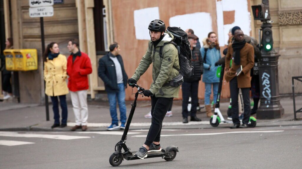 Homme en trottinette électrique en ville, soulignant l'importance de l'assurance et de la responsabilité civile